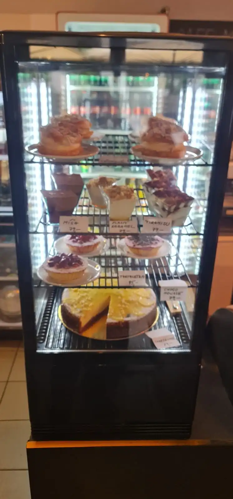 Glass cake display fridge with cheesecakes and cakes, portrait.