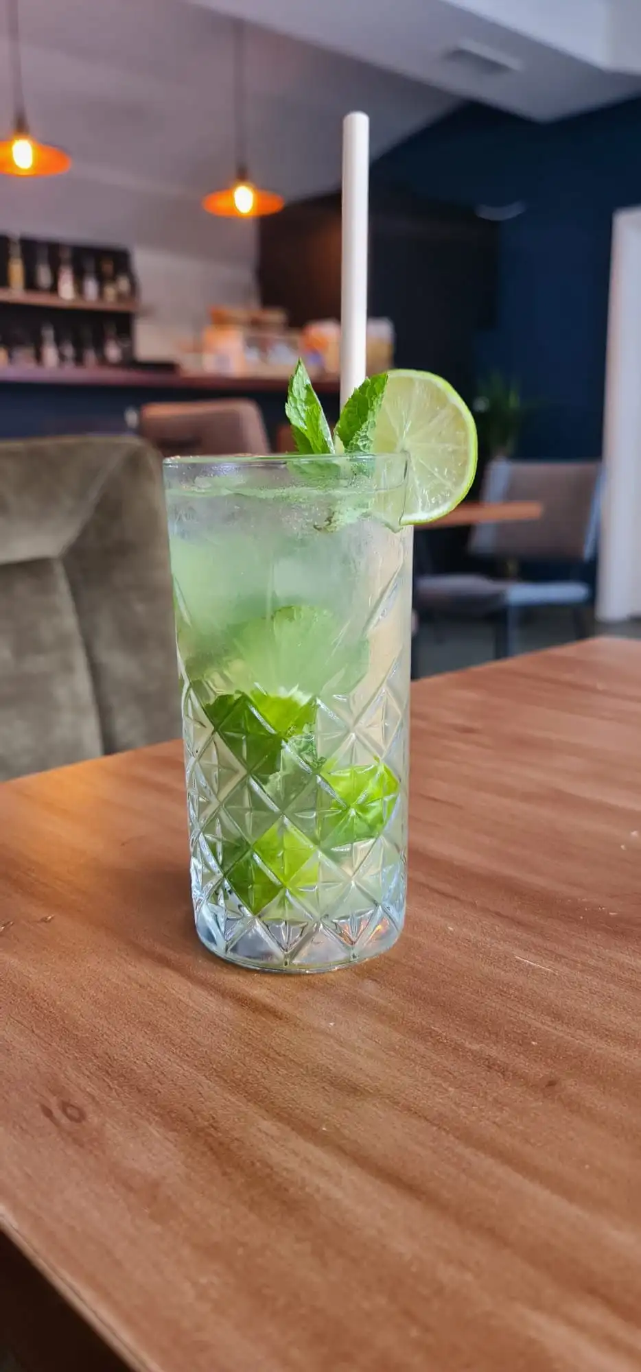 Mojito in a cut-glass tumbler with lime and mint, paper straw.