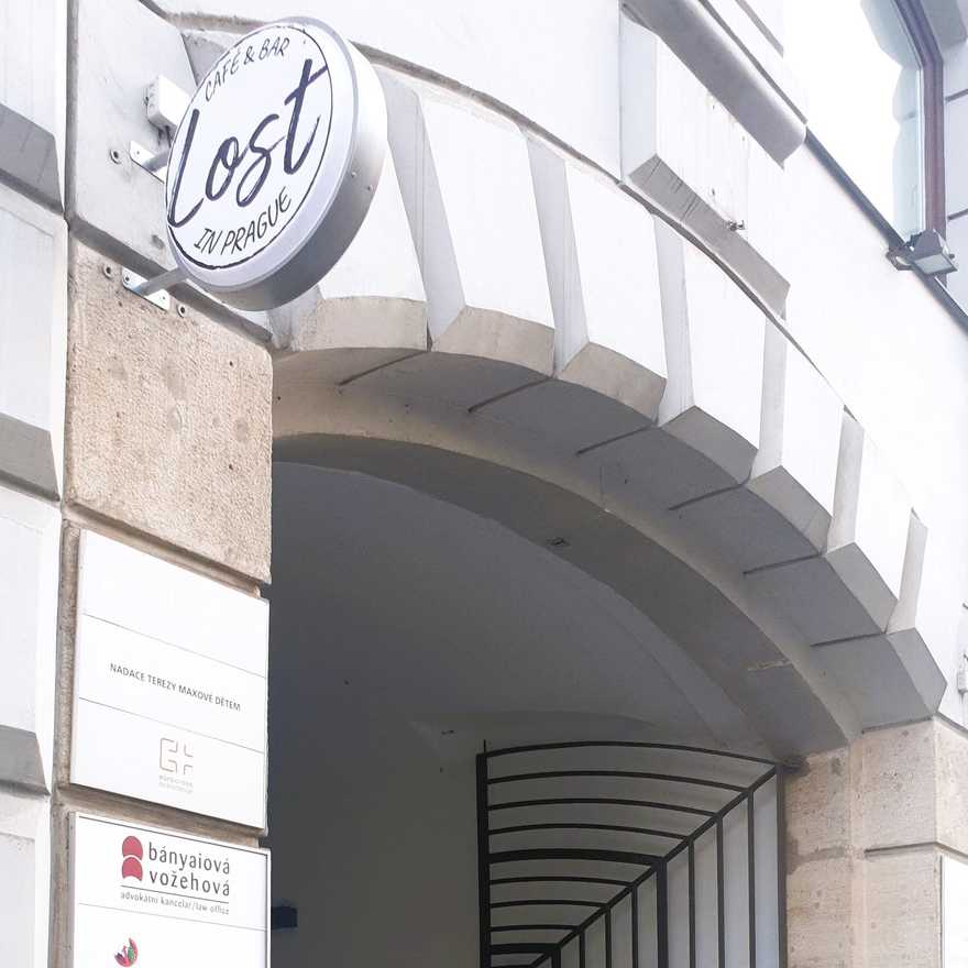 The round Lost in Prague sign above the stone archway of the street entrance on Lazarská.