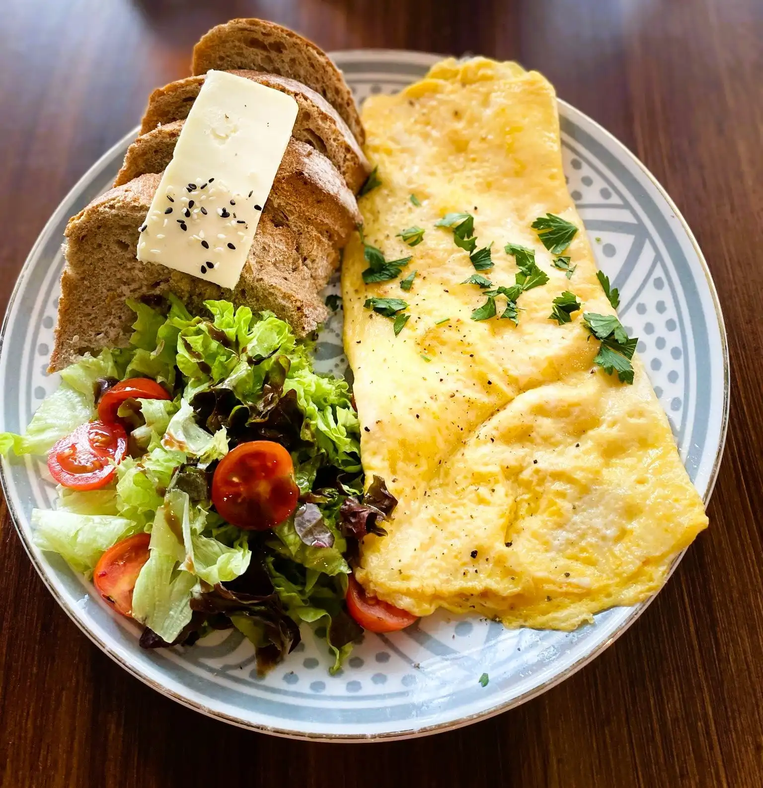 Cheese omelette with herbs, sourdough slices with butter and salad with cherry tomatoes.